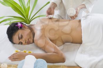 Massage therapist applying massage cream on a young woman's back