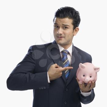 Businessman pointing at a piggy bank
