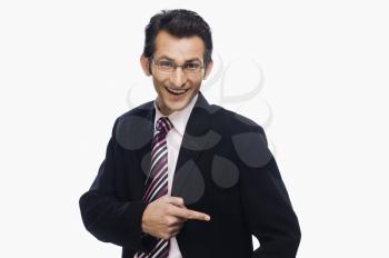 Portrait of a businessman pointing at his pocket and smiling