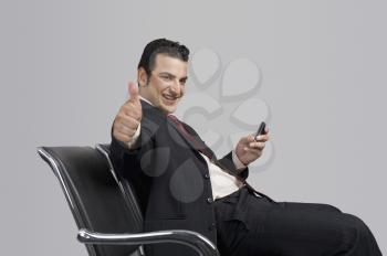 Businessman holding a mobile phone and showing thumbs up sign
