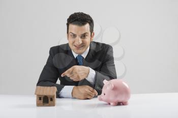 Businessman with a model home and a piggy bank