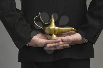 Mid section view of a businessman holding a magic lamp