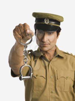 Portrait of a policeman holding a pair of handcuffs