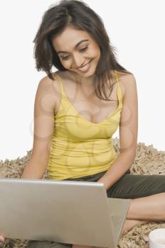 Woman sitting on a rug and working on a laptop
