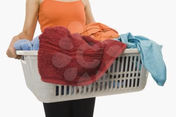 Mid section view of a woman holding laundry basket filled with clothing