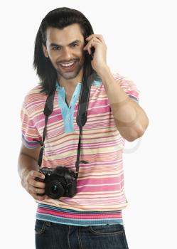 Photographer holding a digital camera and talking on a mobile phone