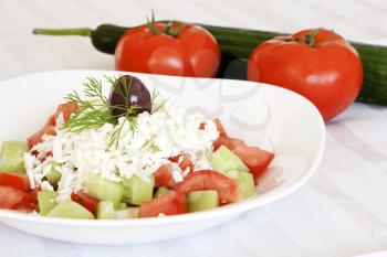 Fresh Mediterranean salad with tomatoes, cucumber, onion, feta cheese and olive on top.
