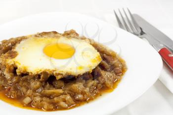 Delicious stew with baked onion, egg and sausages