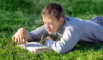Royalty Free Photo of a Boy Lying on the Grass Reading a Book