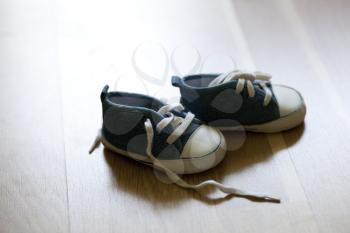 A pair of children blue sneakers on wooden surface