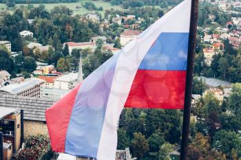 Slovenian national flag fluttering over Lake Bled and town