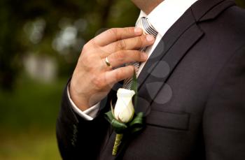 The groom in a suit, corrects a tie with his hand. Close-up composition