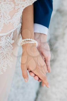 The groom gently holds the bride by the hand, close-up