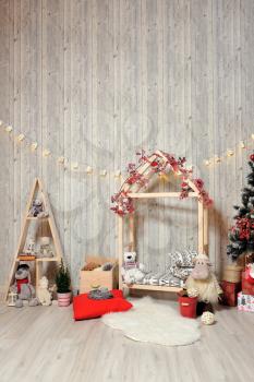 New Year or Christmas photo zone for children. Children's photo zone with a wooden house, toys, a Christmas tree and gifts in a warm light.