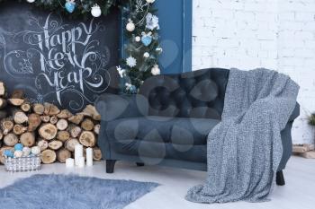 Beautiful New Year's decor. Preparing for the new year, a beautiful room framed for the new year, sofa, blanket, fireplace, inscription in chalk - happy new year.