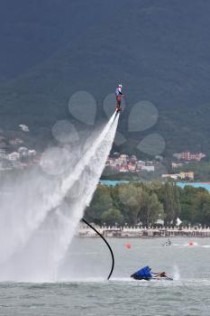 Beautiful show on the water, sports team fly on flyboards in the sea against the background of the mountains