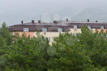 residential building with a wet roof after the rain against the backdrop of mountains in the fog