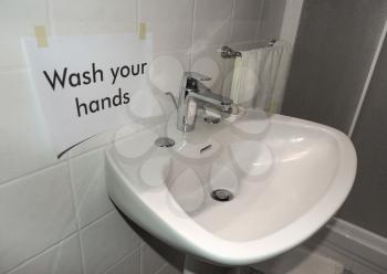 Wash your hands sign near bathroom basin