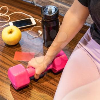 Woman holding pink dumbbell with smartphone headset apple water bottle