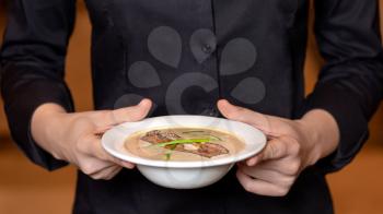 Waiter holding beautiful mushroom soup