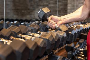 Unrecognizable man taking dumbbell in a gym close up