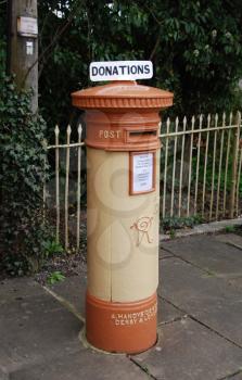 Royalty Free Photo of an Orange and Vintage British Postbox on the Sidewalk