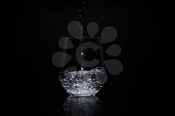 pouring water in a clear glass on a black background