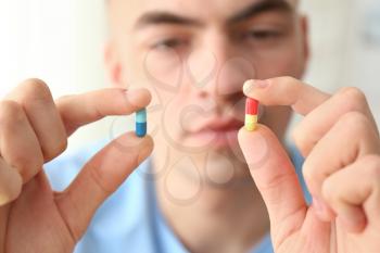 Young man holding different pills, closeup�