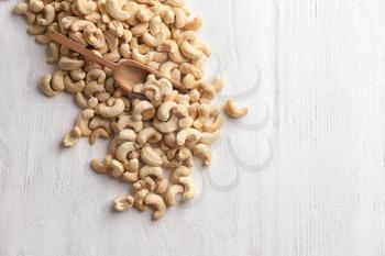 Tasty cashew nuts on white wooden background�