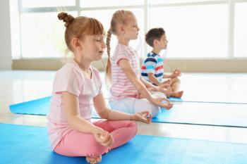 Little children practicing yoga indoors�