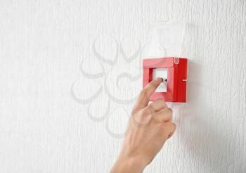 Young man using fire alarm system indoors�