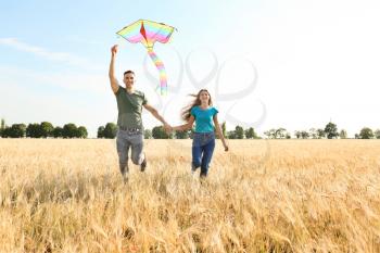 Happy young couple flying kite in a field�