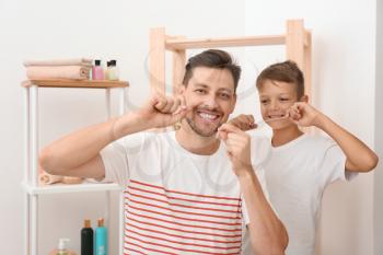 Little boy and his father flossing teeth in bathroom�