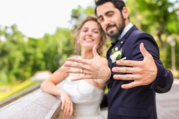 Happy newlyweds showing their wedding rings outdoors�