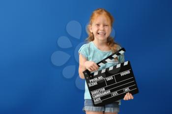 Cute little girl with clapper board on color background�