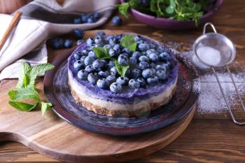 Plate with delicious blueberry cheesecake on wooden table�