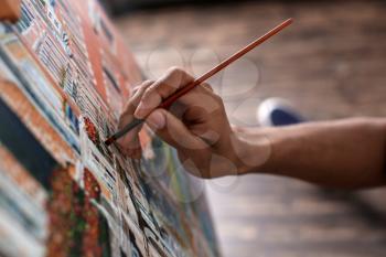 Young African-American artist painting picture in workshop, closeup�