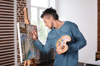 Young African-American artist painting picture at home�