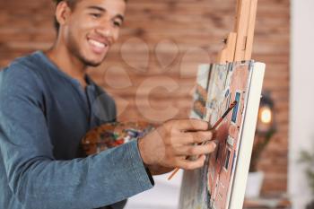Young African-American artist painting picture at home�