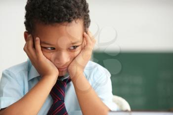 Bored African-American boy unwilling to study in classroom�