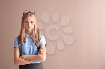 Displeased schoolgirl on color background�