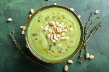 Bowl with tasty zucchini soup and peanuts on color table�