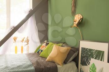 Interior of modern comfortable bedroom with golden tropical leaves on color wall�