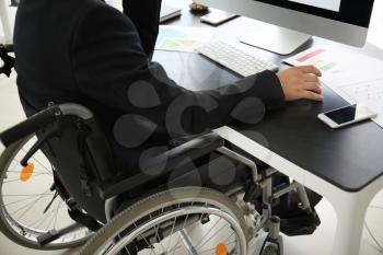 Businessman in wheelchair working with computer in office�
