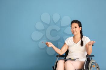 Female teacher in wheelchair on color background�
