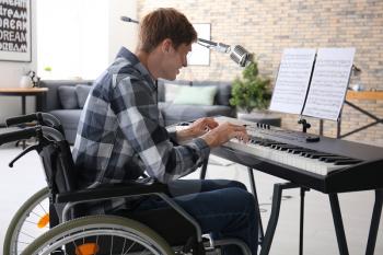 Young musician in wheelchair playing synthesizer at home�