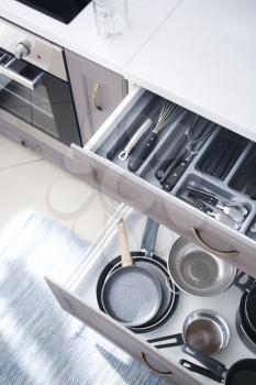 Set of clean kitchenware and utensils in open drawers�