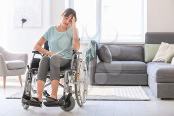 Depressed young woman in wheelchair at home�