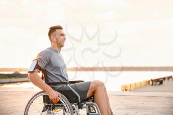 Young man in wheelchair listening to music outdoors�
