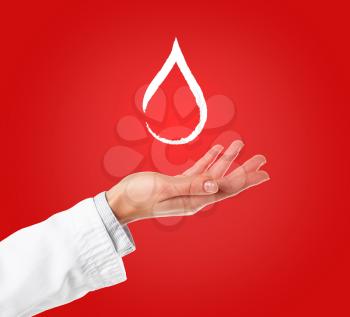 Hand of female doctor with drop of blood on color background�